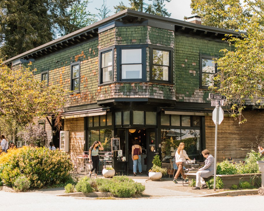 Two-story building with weathered shingle siding converted to street-level cafe with outdoor seating