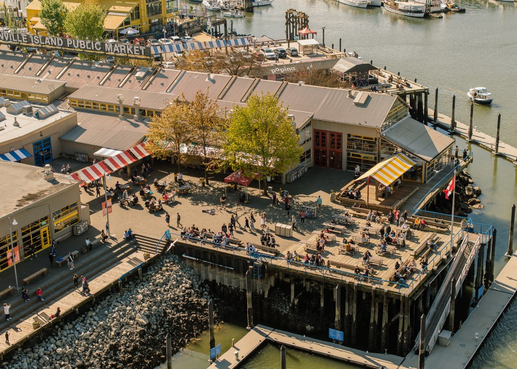 Granville Island Public Market waterfront with outdoor seating area and boats in Vancouver harbor