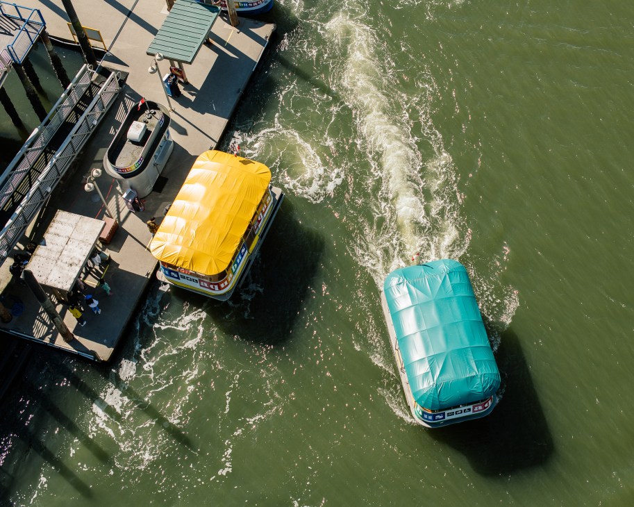 Aerial view of two colorful inflatable water slides - one yellow, one turquoise - at a waterfront dock facility