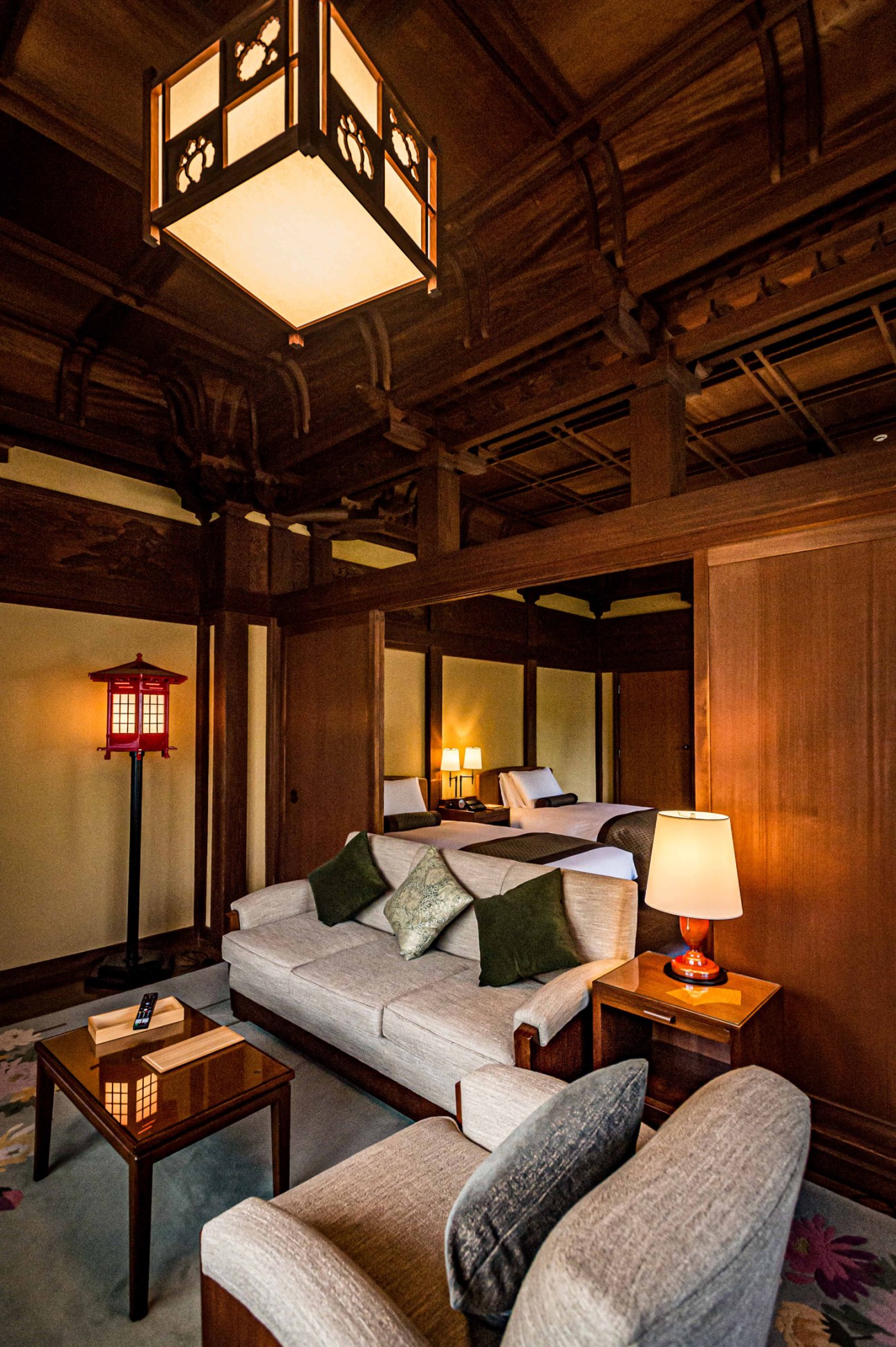 Traditional Japanese hotel room with tatami floors, wooden ceiling beams, paper lanterns and neutral furnishings