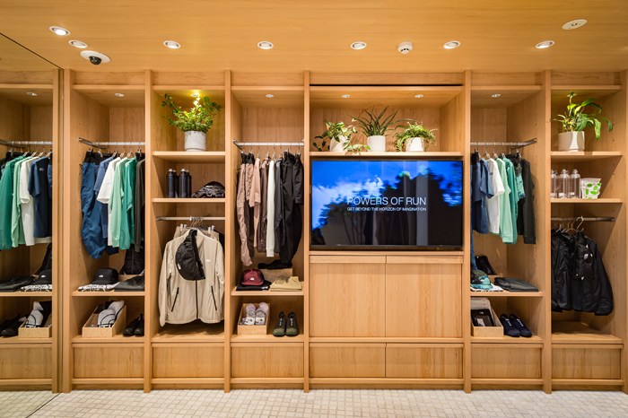 Interior of The North Face Sphere store with wooden shelving displaying running gear, plants, and a screen showing 'Powers of Run'.