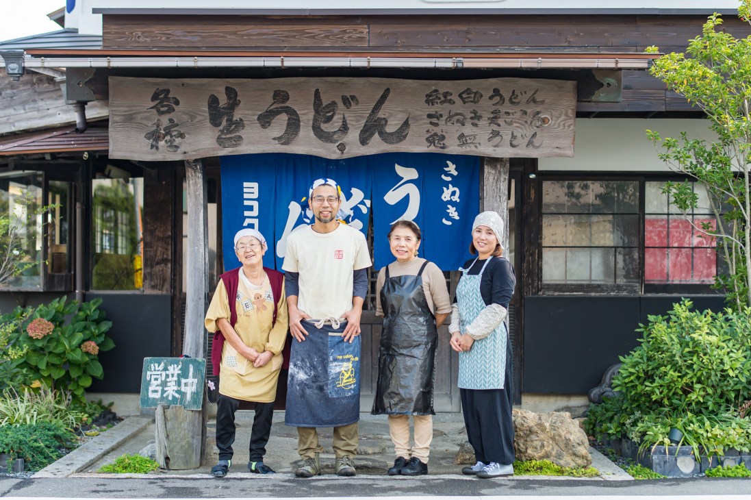 Four staff members of Yokokura udon restaurant standing in front of their traditional shop entrance