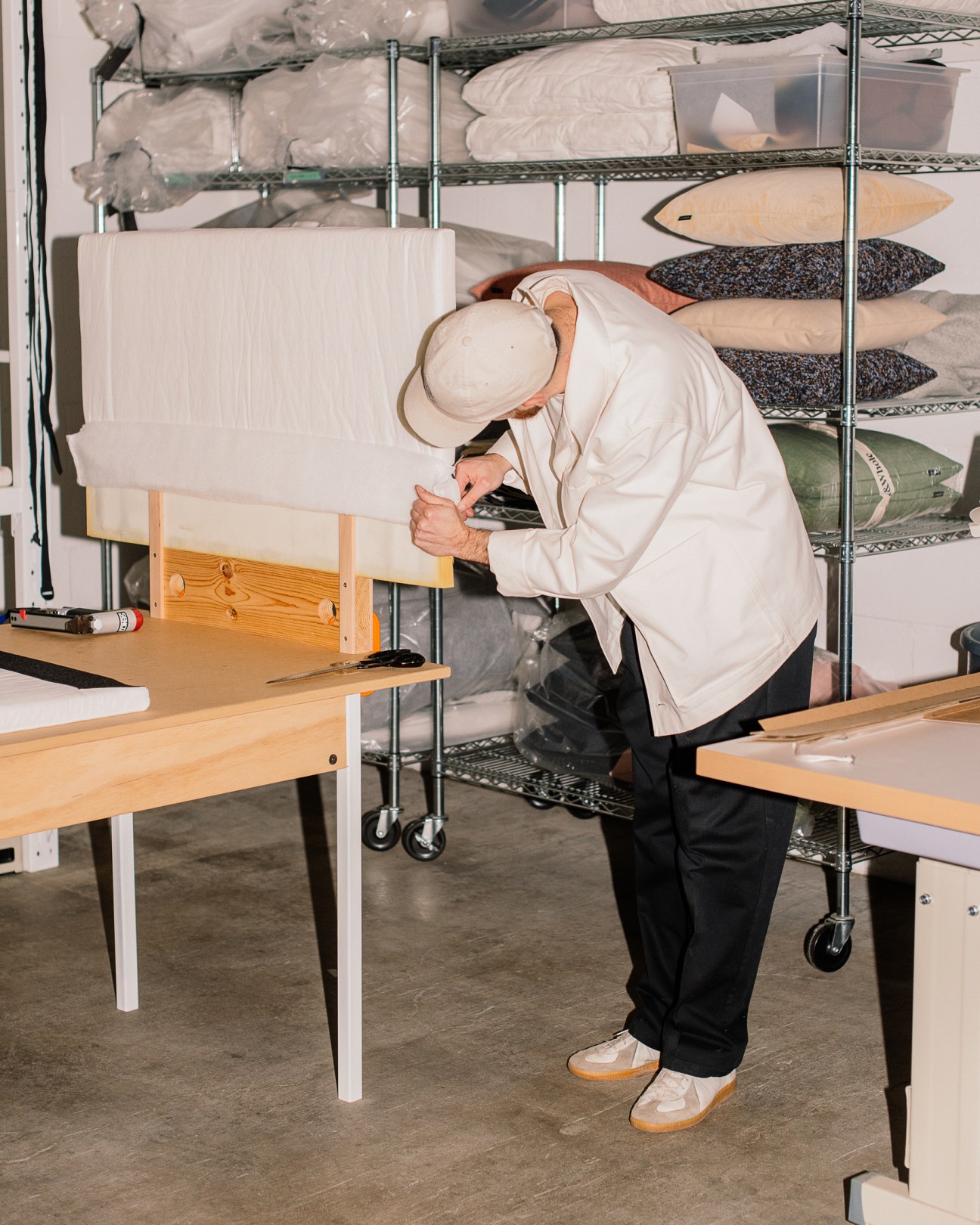 Craftsperson working on Part & Whole modular sofa frame with tools at wooden workbench.