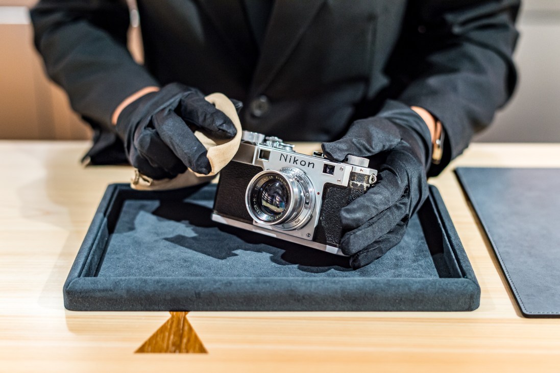 Technician in gloves carefully cleaning a vintage Nikon camera in Kitamura Camera's repair studio