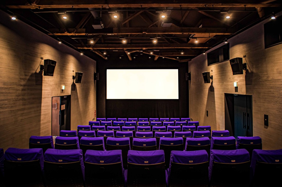 Interior view of Cinema Neko showing intimate screening room with purple velvet seats and projection screen