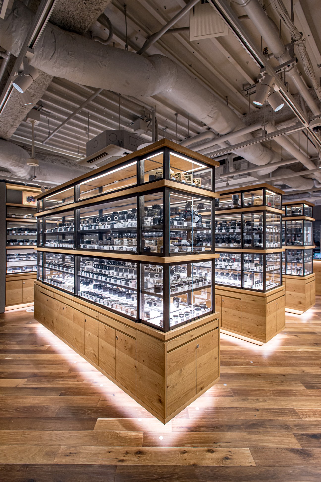Modern camera store interior with glass display cases containing vintage cameras on wooden floors