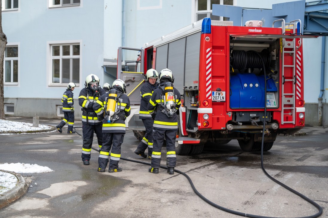 Firefighters in protective gear conduct a training exercise with a red fire truck at Sim Campus in Eisenerz, Austria.