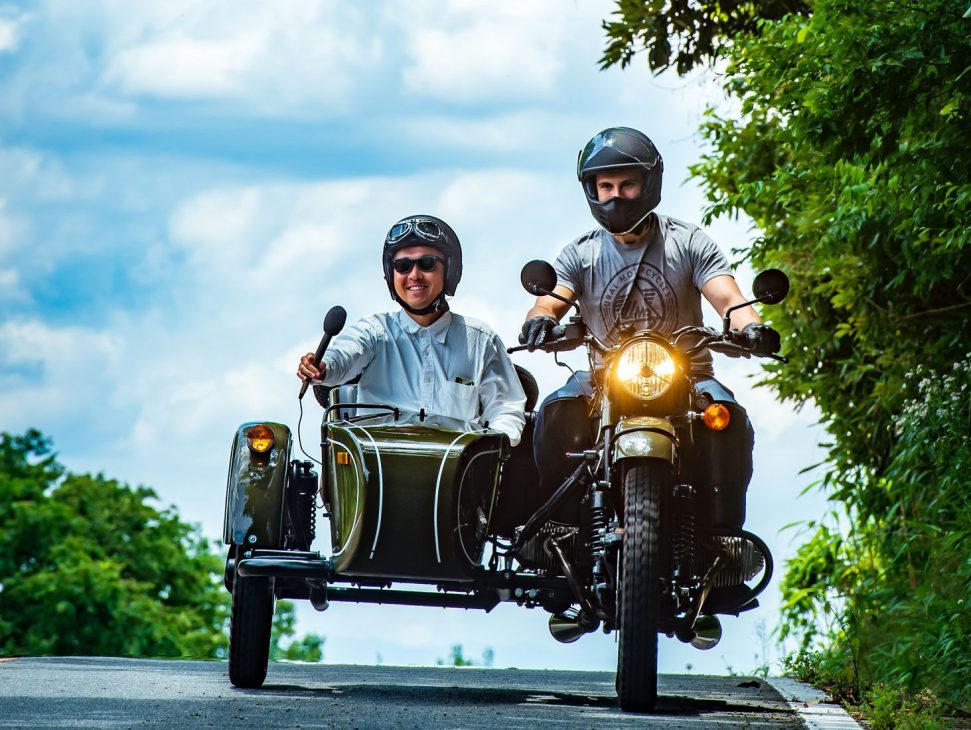 Man with helmet and goggles sitting in motorcycle sidecar recording with microphone