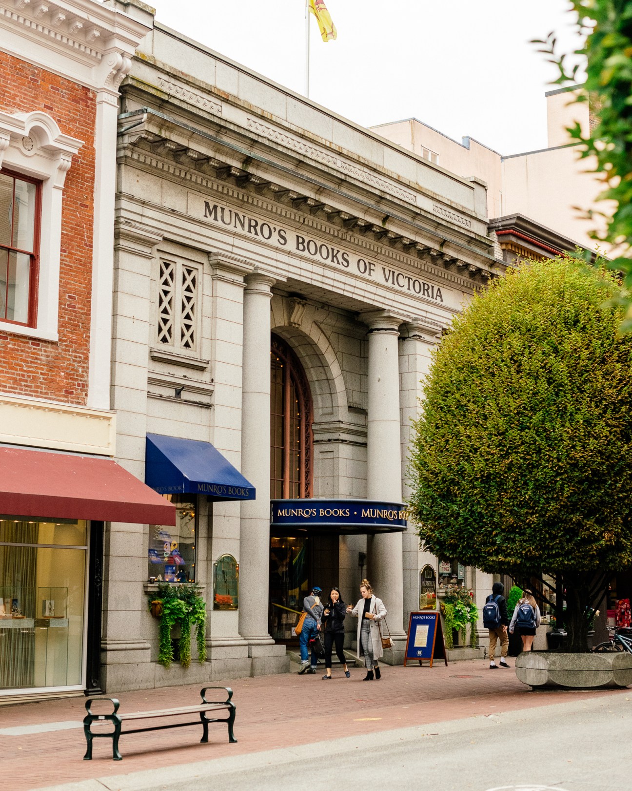 Munro's Books storefront with stone columns and blue awning in Victoria, Canada