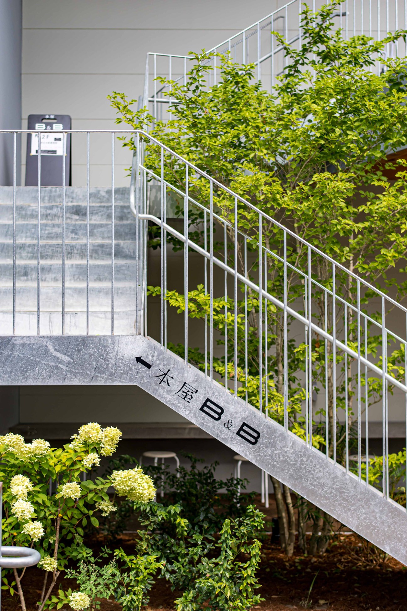 Modern staircase with metal railings and landscaped garden area featuring flowering plants