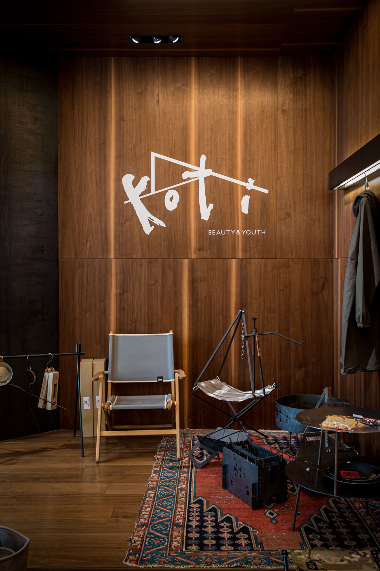 Display of outdoor gear and clothing from Koti collection including jackets, bags and accessories arranged on white surfaces