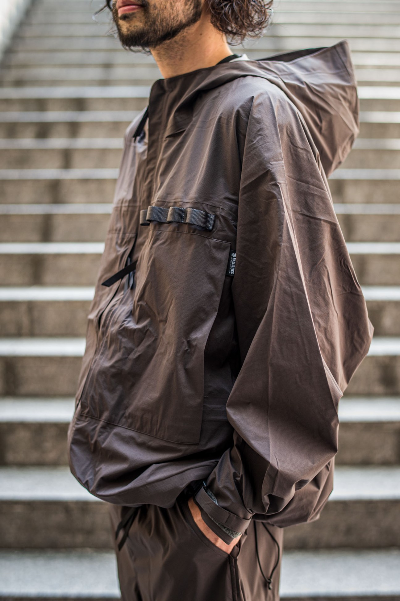 Dark green all-weather jacket and matching trousers from Koti outdoor collection displayed on hangers