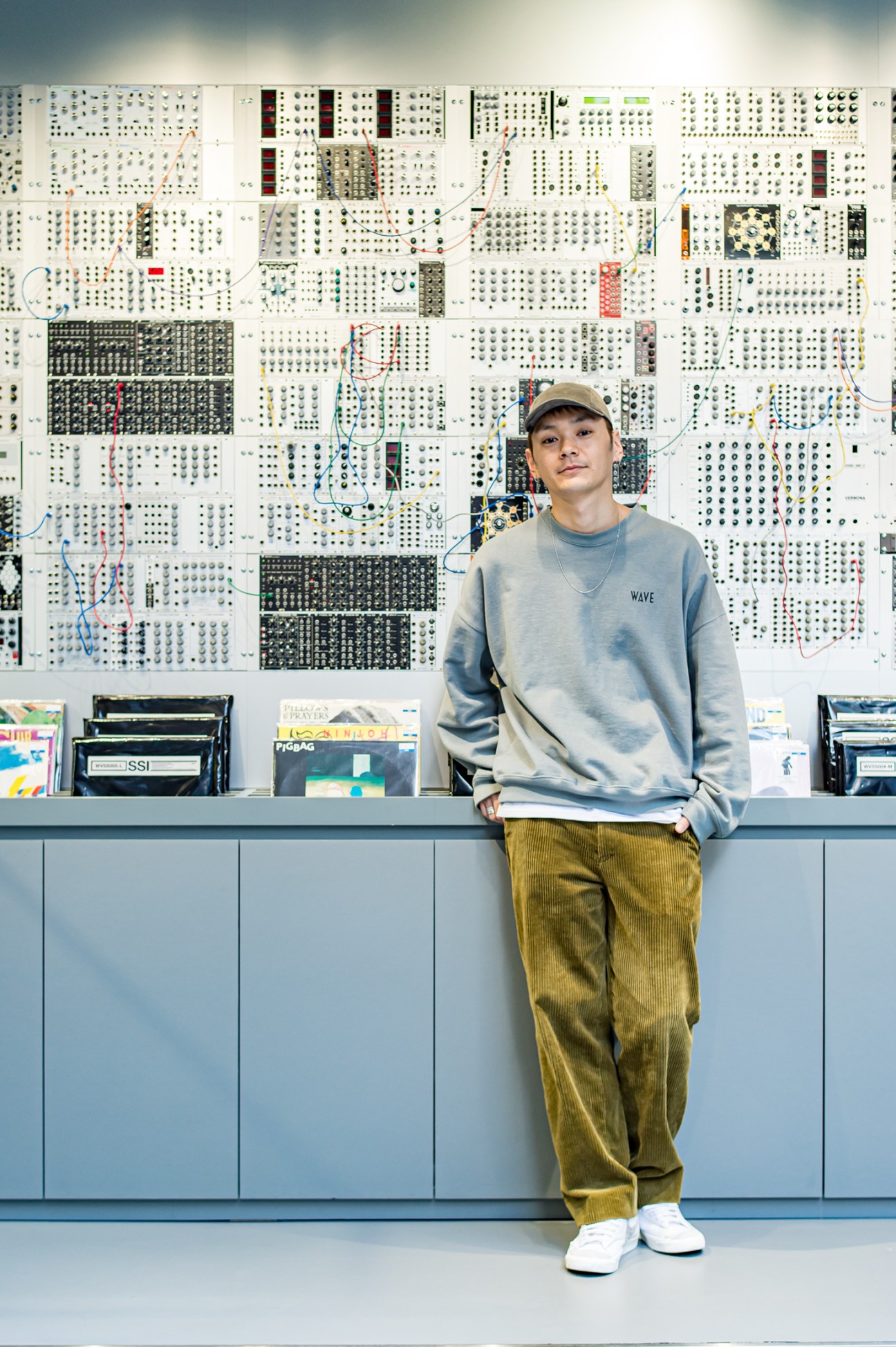 Customer at Wave record shop standing against modular synthesizer wall display