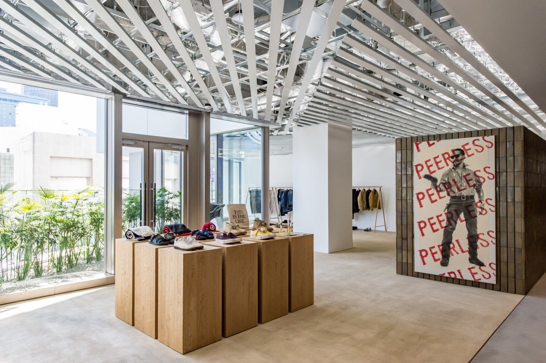 Interior of Peerless Visvim shop with wooden display blocks, shoes, exposed ceiling beams and large branded wall graphic