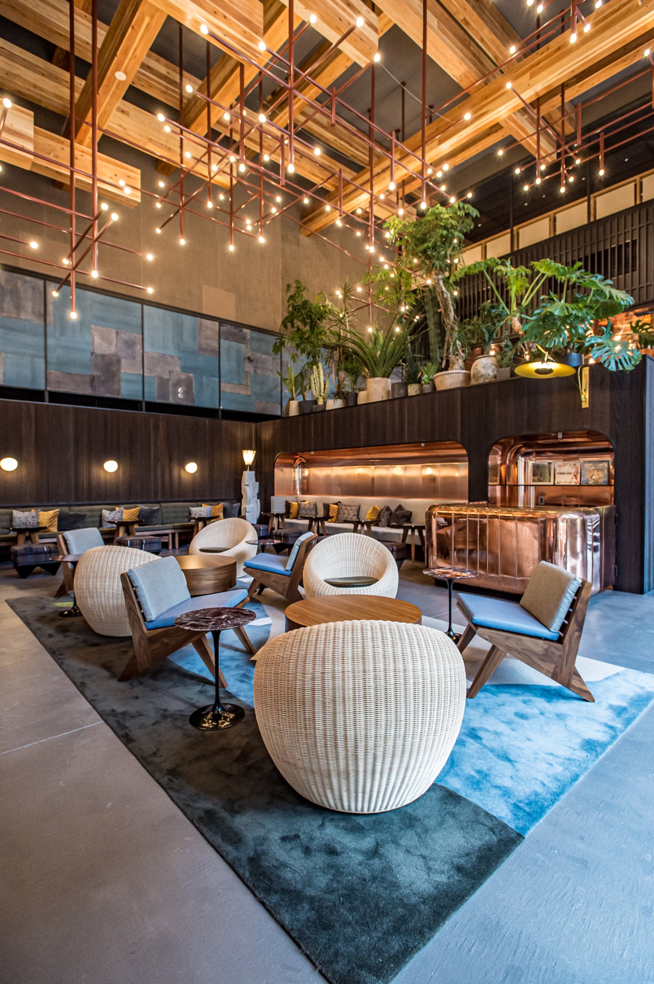Modern hotel lobby with wicker chairs by Isamu Kenmochi, string lights, and plants