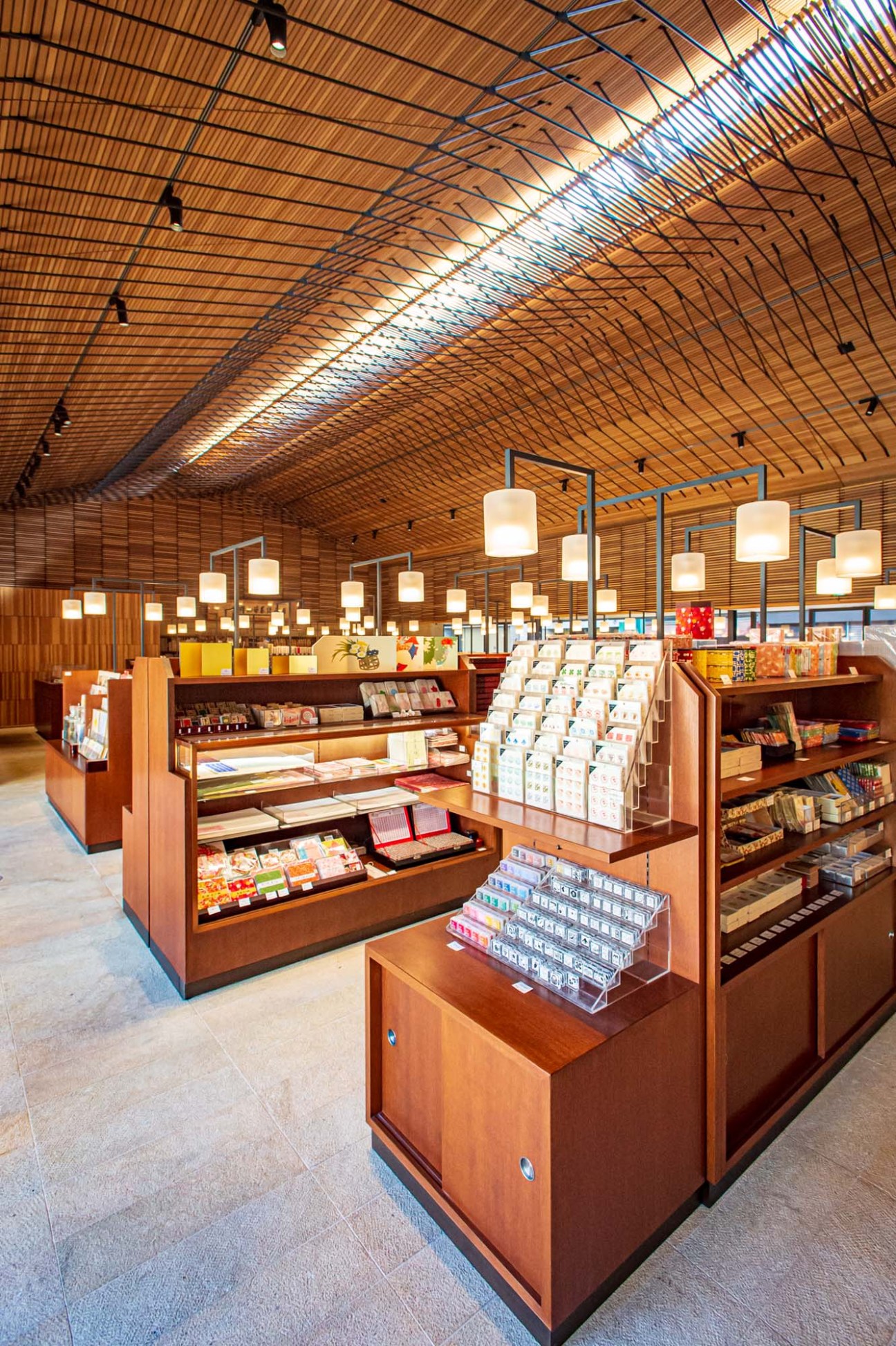 Interior of Kyukyodo shop in Kyoto showing wooden slatted ceiling, hanging pendant lights, and wooden display cases with products