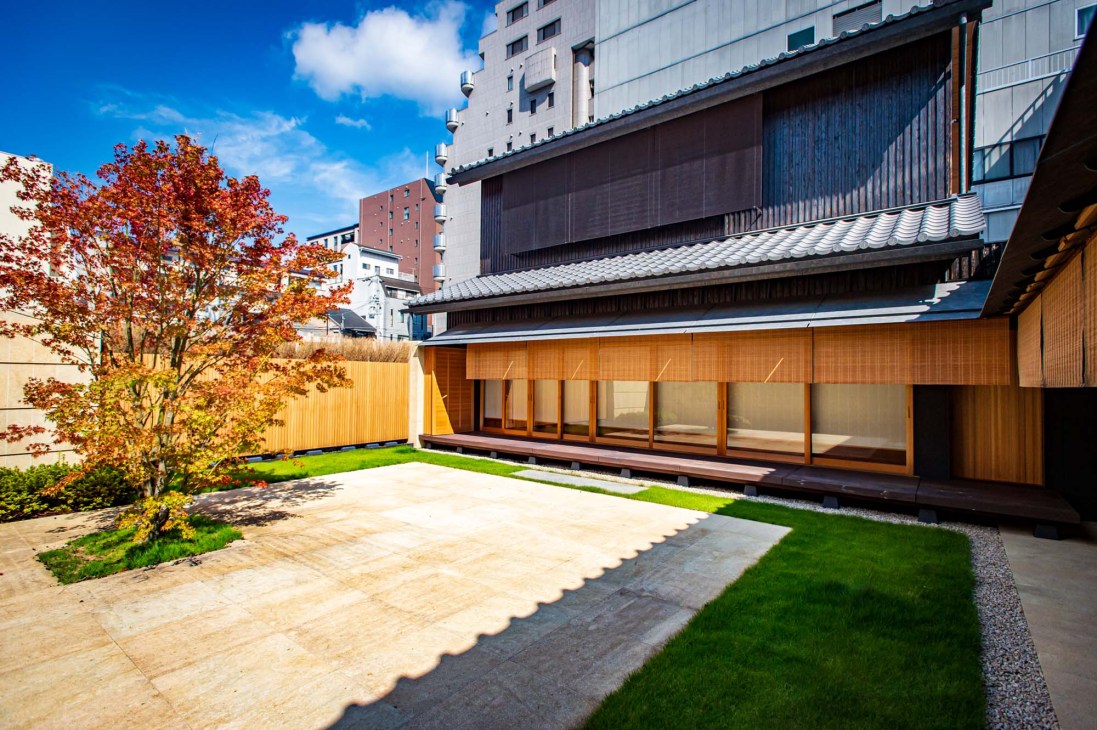 Garden courtyard at Kyukyodo shop designed by Hiroshi Naito with wooden architecture and autumn foliage.