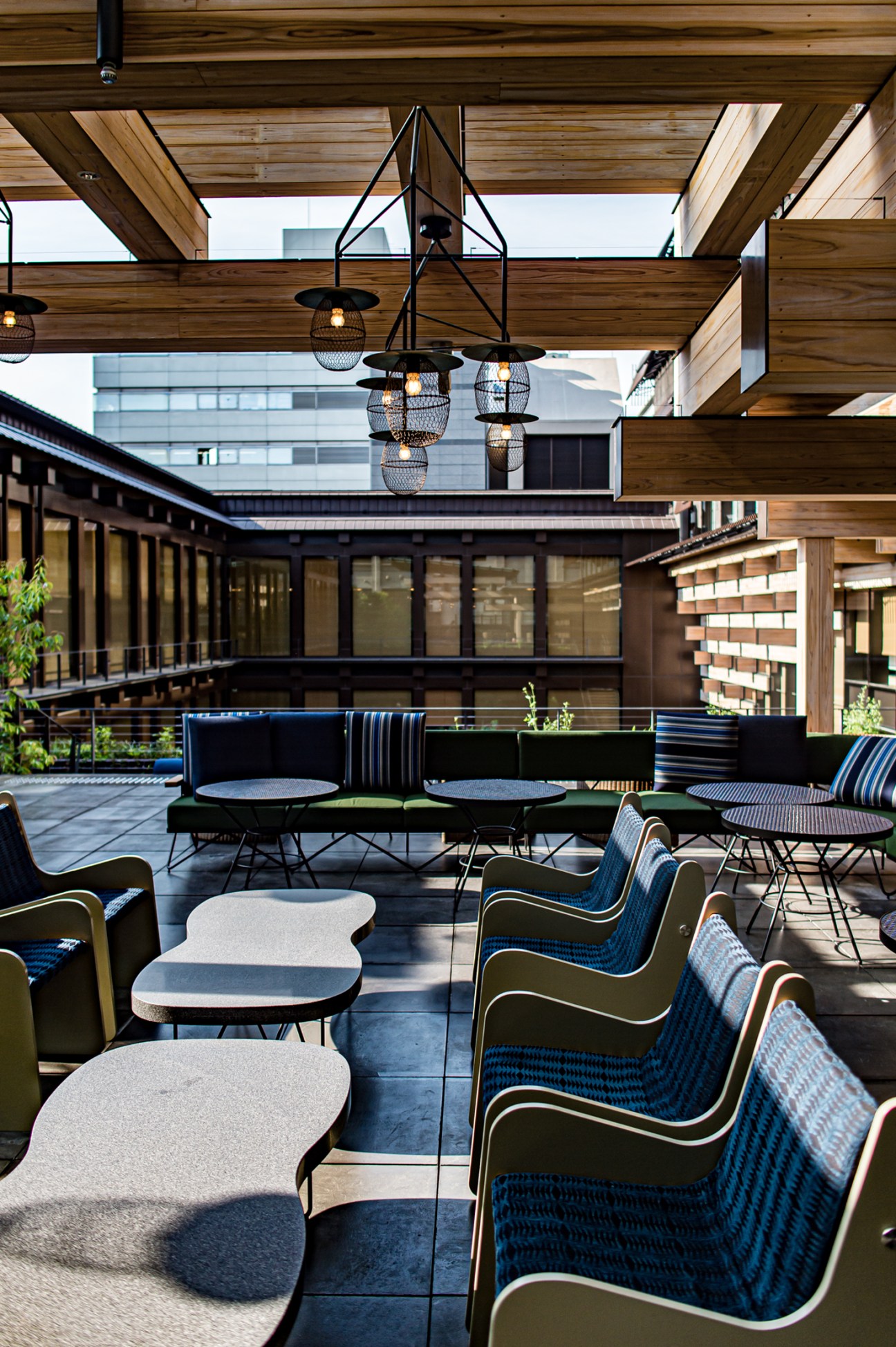Modern outdoor terrace with wooden pergola, pendant lights, and contemporary seating overlooking urban buildings
