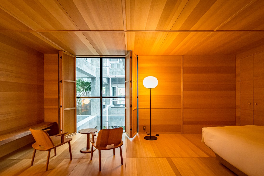 Minimalist wooden hotel room interior with two chairs, small table, floor lamp and large window