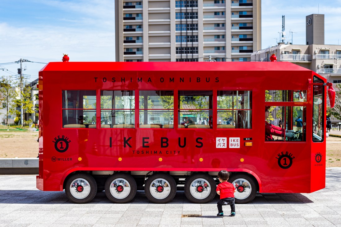 Child looking excitedly at the bright red Ikebus on city street