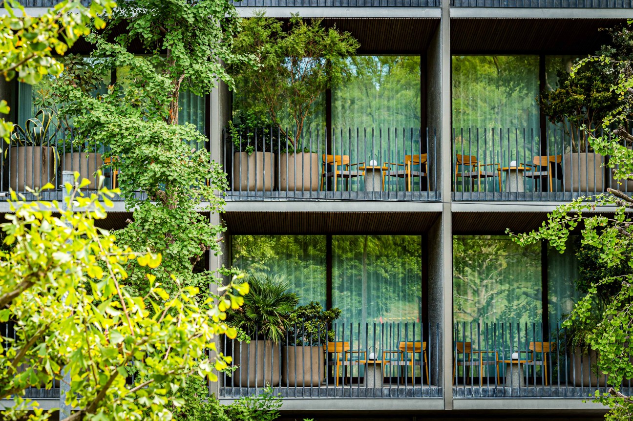 Dense green foliage and plants surrounding the hotel building creating a natural urban oasis