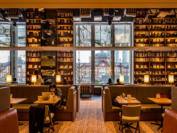Interior view of Share Lounge Marunouchi showing café area with large windows overlooking Tokyo Station's red-brick façade
