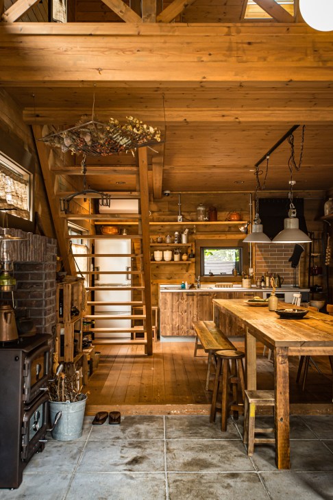 Wooden kitchen interior in a Bess Country Log home with exposed beams, shelving, and dining table.