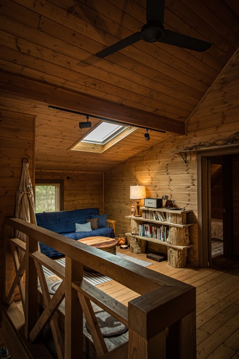 Wooden interior of a Bess Country Log house with blue sofa, shelving, and skylight.