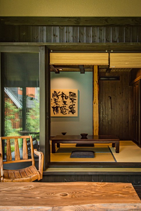 Japanese-style tatami room in a Bess Hodo-hodo house with wooden furniture and calligraphy artwork.
