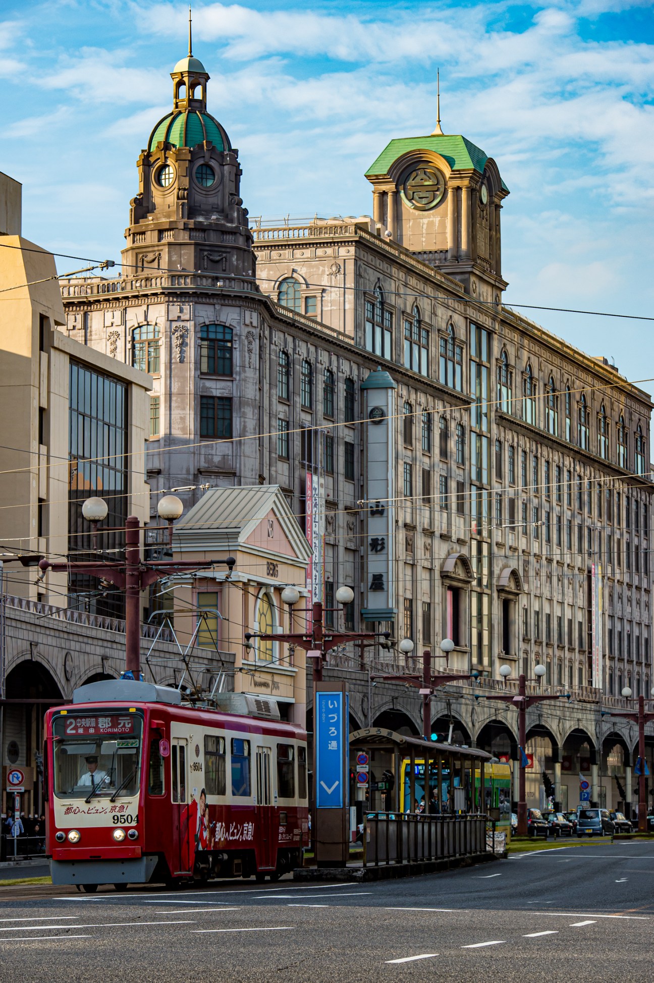 Historic Yamakataya department store building with ornate architecture and green domed towers, with red tram in foreground