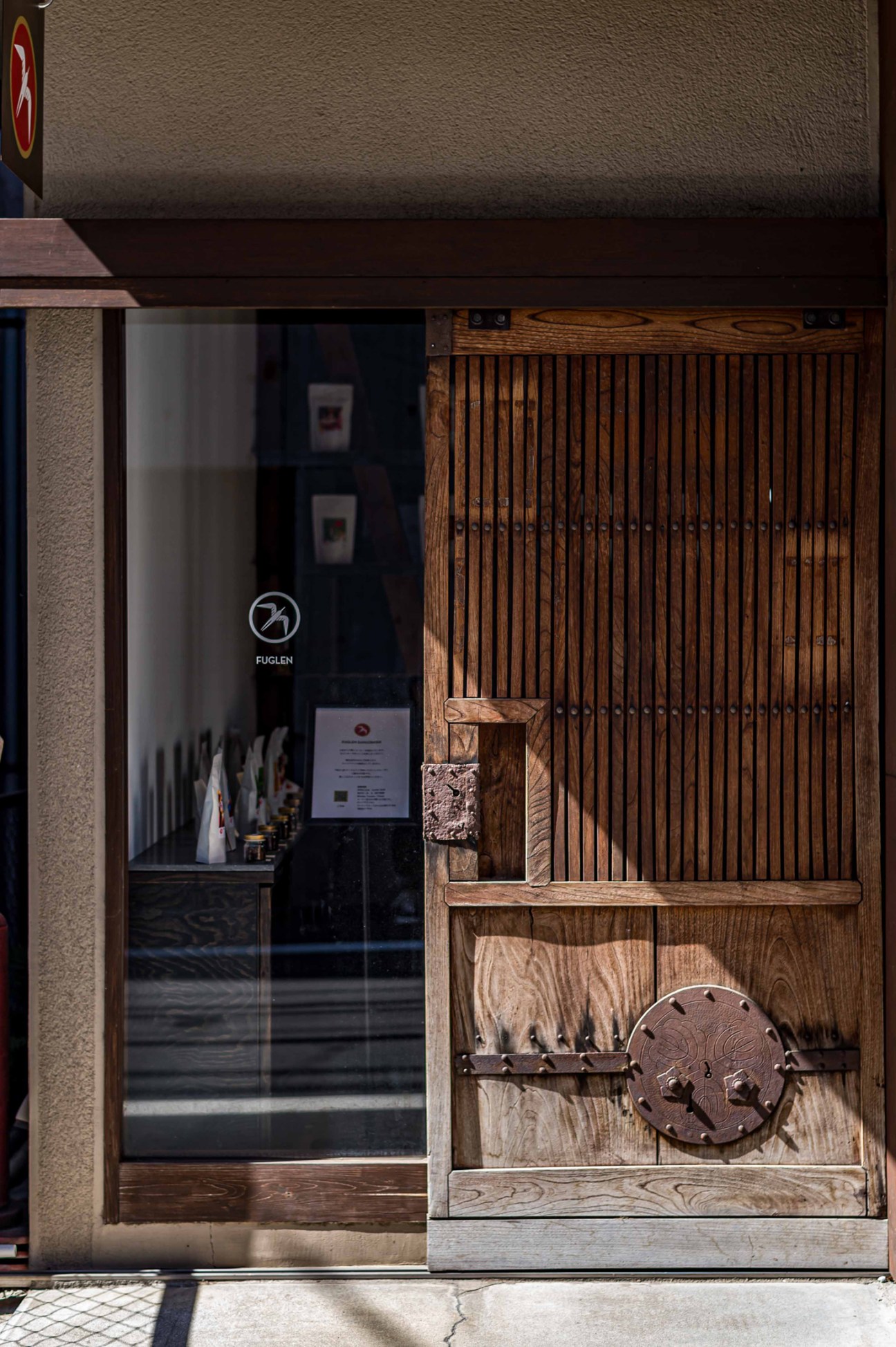 Storefront of Fuglen restaurant in Tokyo with wooden door and glass windows.