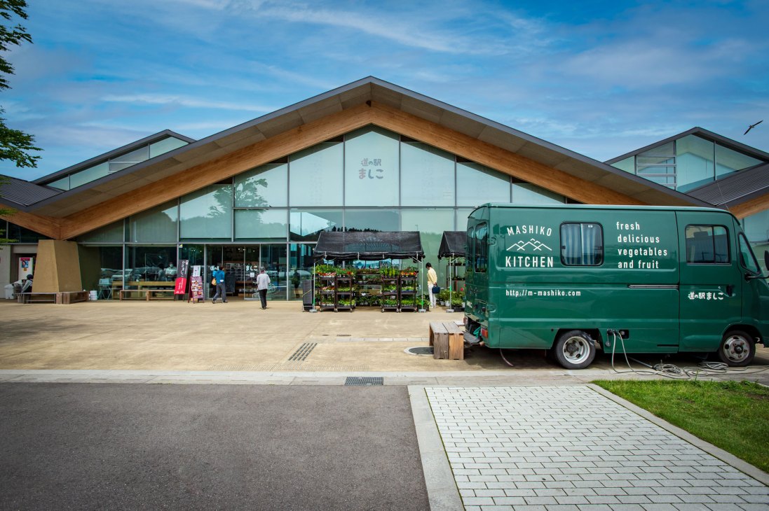 A green Mashiko Kitchen food van parked outside the modern wooden architecture of Mashiko Roadside Station in Japan.