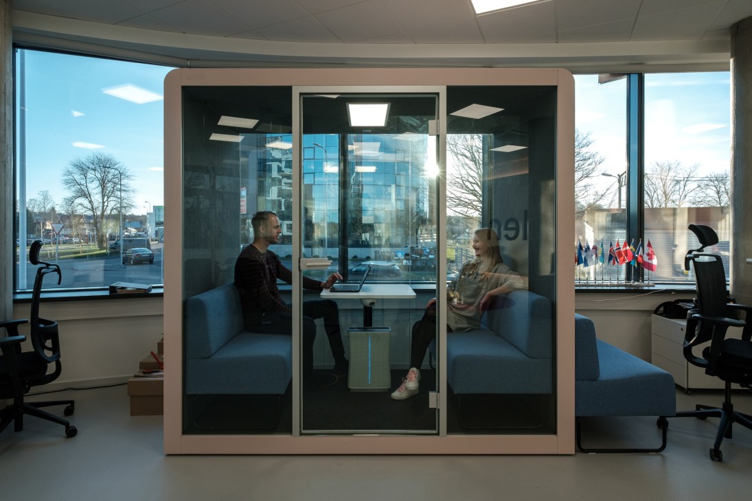 Two people having a meeting inside a glass-walled Silen office pod in a modern open-plan office space