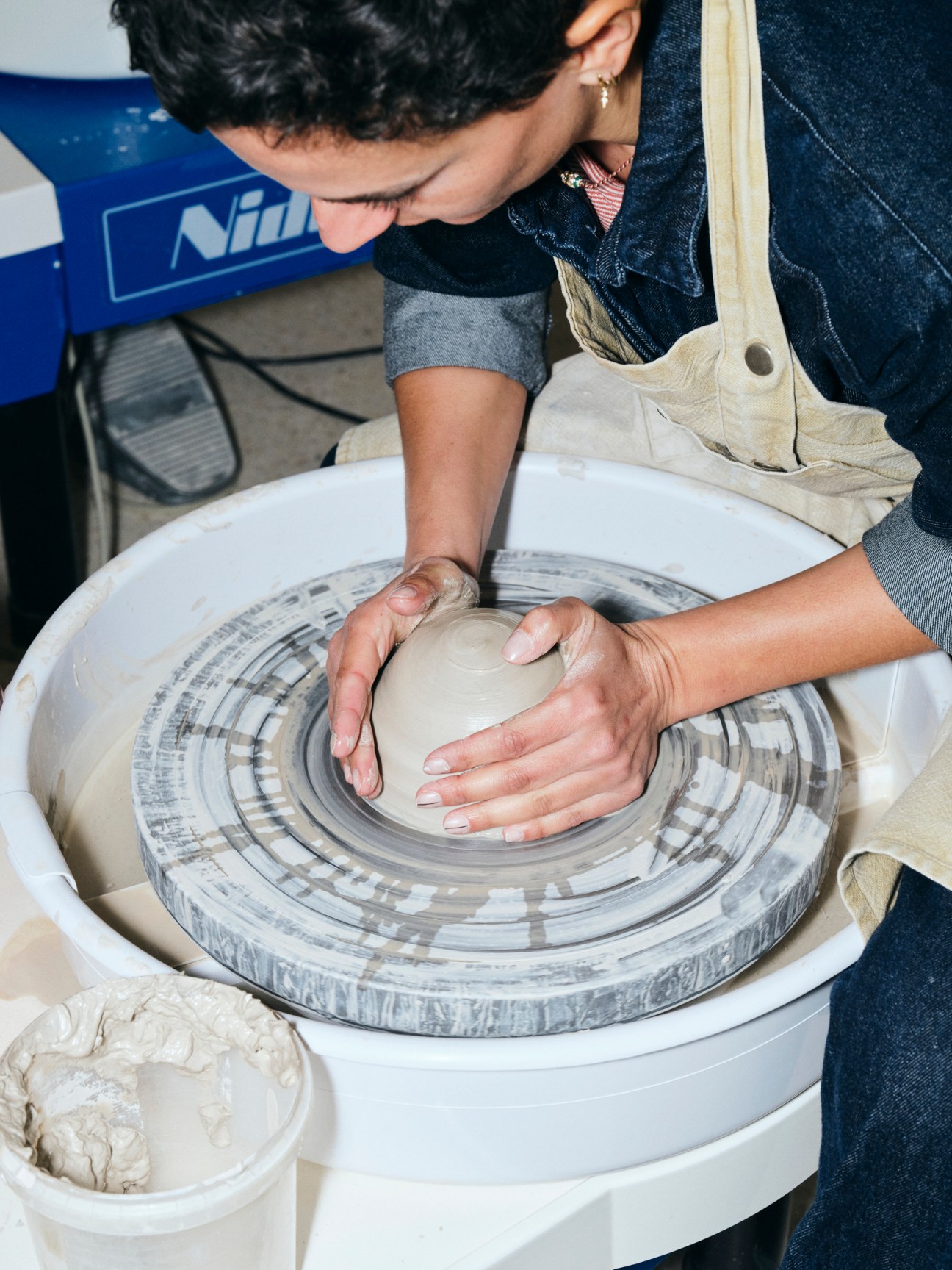 Hands working clay on a pottery wheel at ceramist Camille Lameynardie's Claycraft studio in Montpellier