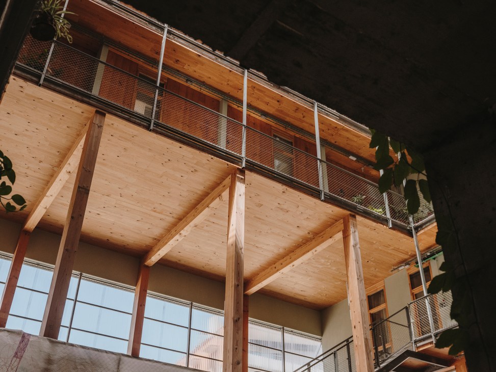 La Borda apartment building exterior showing exposed wooden timber structure and metal railings on balconies.