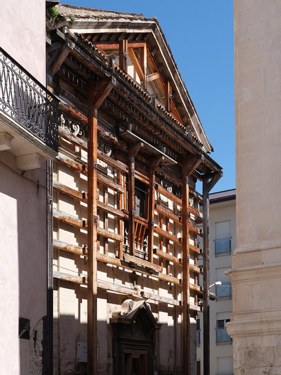 Historic Italian building with ornate wooden scaffolding and balconies during earthquake restoration work