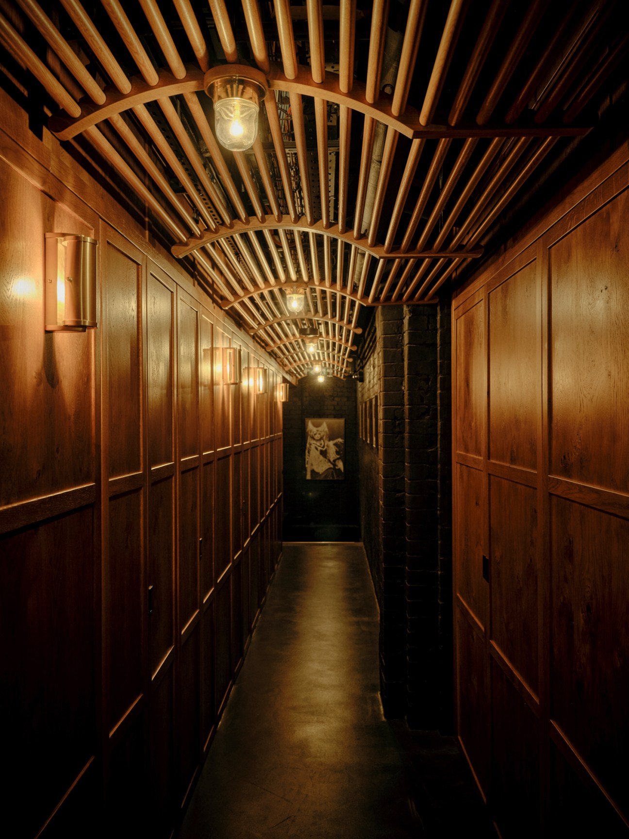 Intimate corridor with warm wood paneling, soft lighting, and cozy seating areas