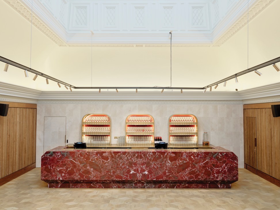 Elegant bar area with red marble counter, illuminated bottle displays, and ornate ceiling in renovated BAFTA headquarters