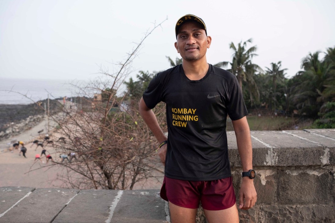 Mukund Vedpathak wearing a black Bombay Running Crew t-shirt and red shorts, standing on a concrete walkway