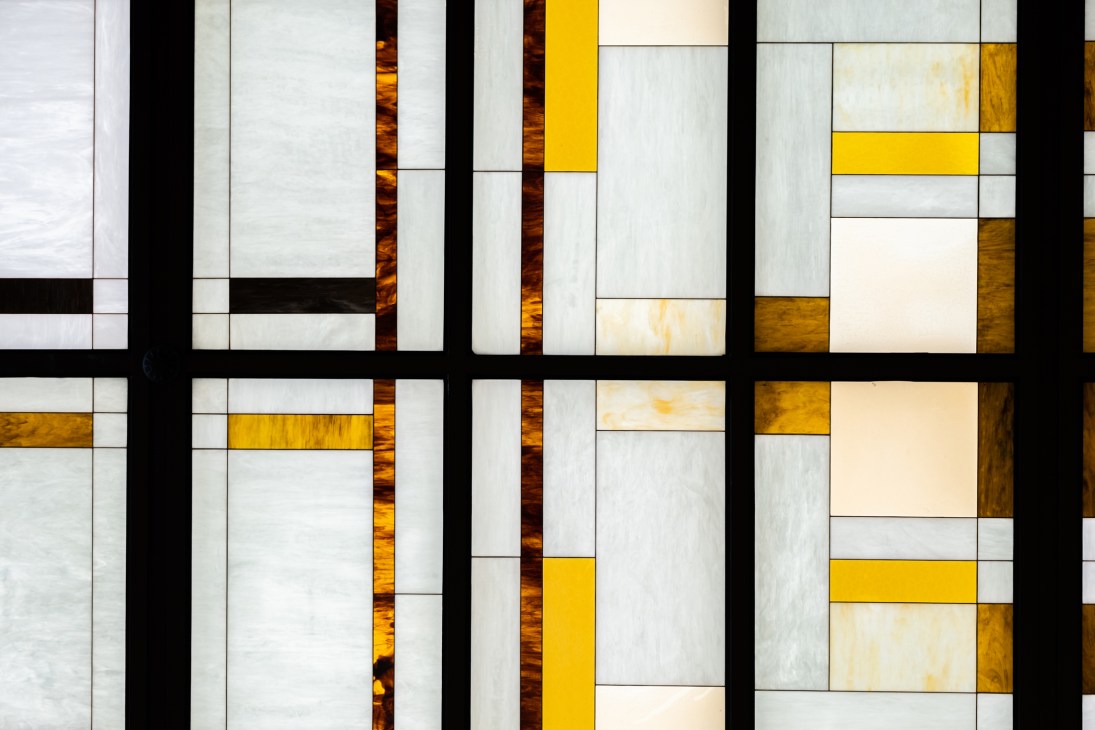 Modern geometric glass ceiling with amber, yellow and clear panels arranged in a grid pattern with black frames