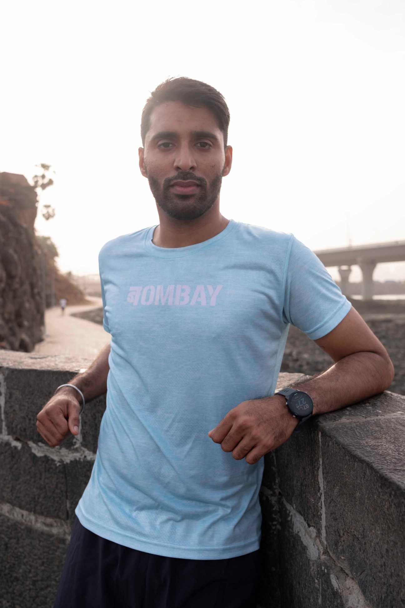 Gaurav Bangera wearing a light blue Bombay Running t-shirt standing by concrete railing outdoors