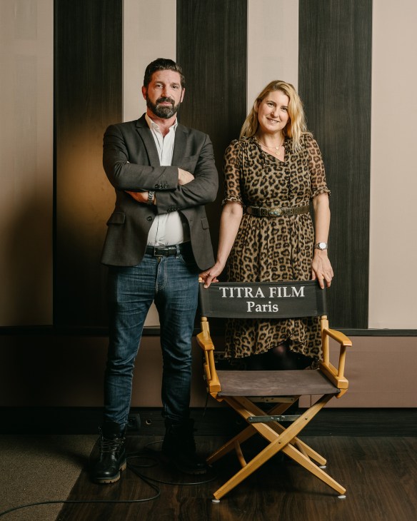 David and Sophie Frilley stand together next to a director's chair labeled Titra Film Paris.