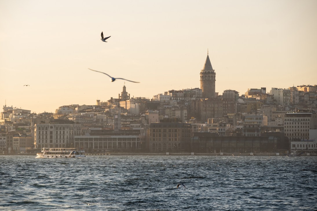 Seagulls flying over the Bosphorus with Istanbul's Galata Tower and Karaköy waterfront skyline at golden hour