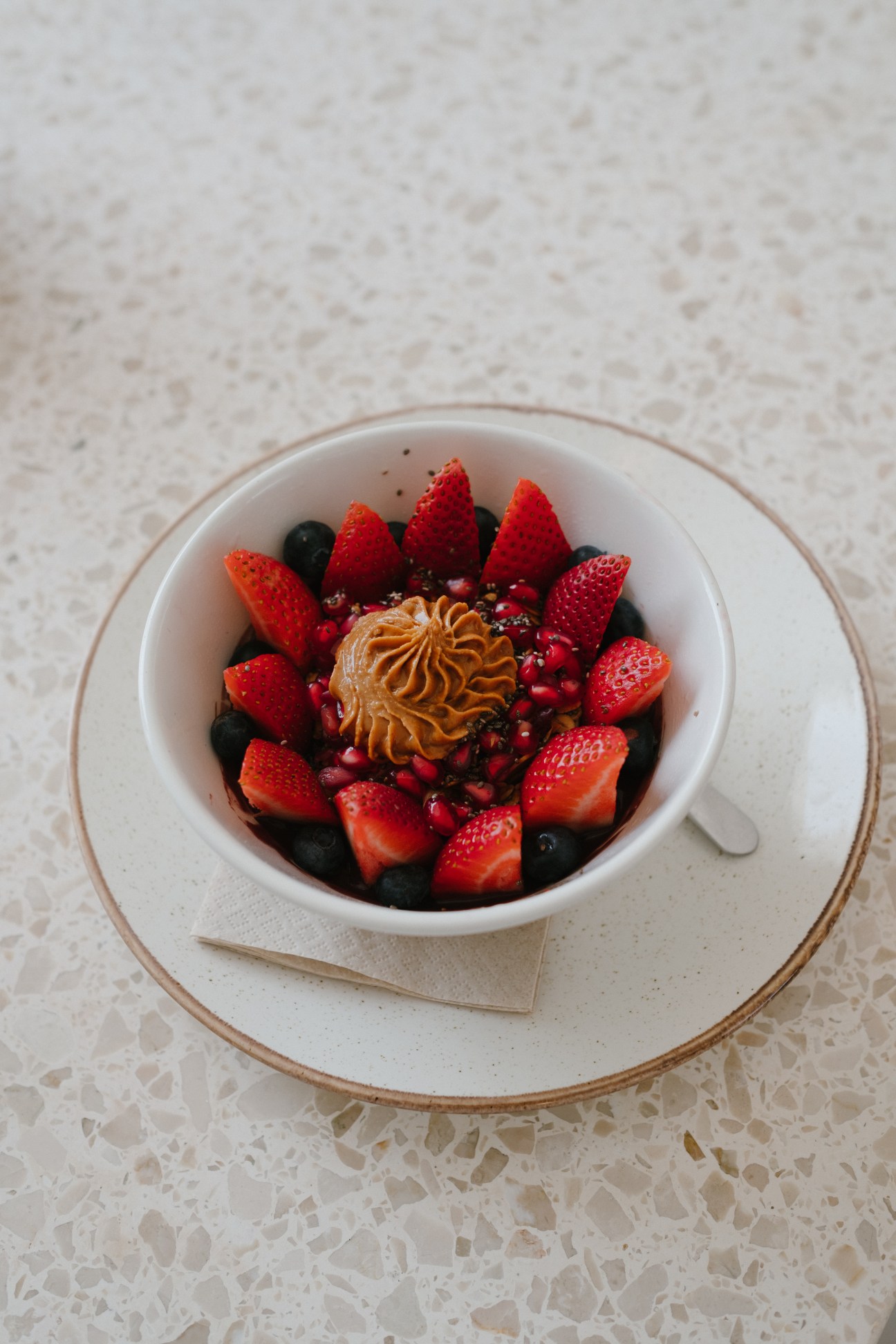 Artfully plated breakfast bowl with fresh strawberries, berries, and decorative cream piping served on white dinnerware