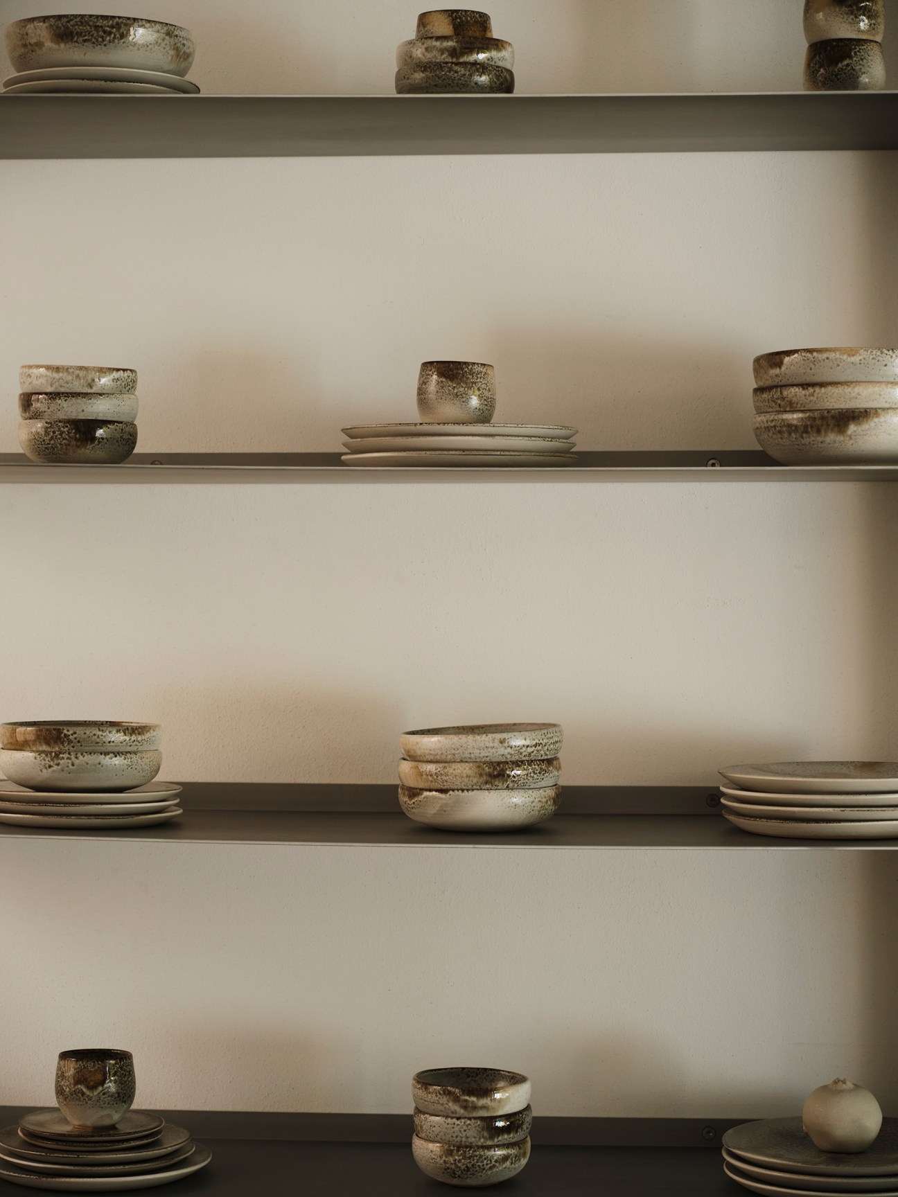 Handcrafted ceramic bowls and vessels in earthy tones displayed on wooden shelving by Danish brand KH Würtz
