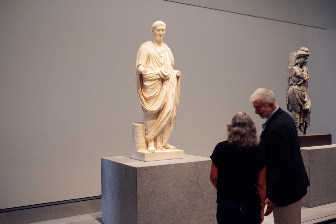 Two visitors viewing Roman marble sculptures in a gallery at the Louvre Abu Dhabi.