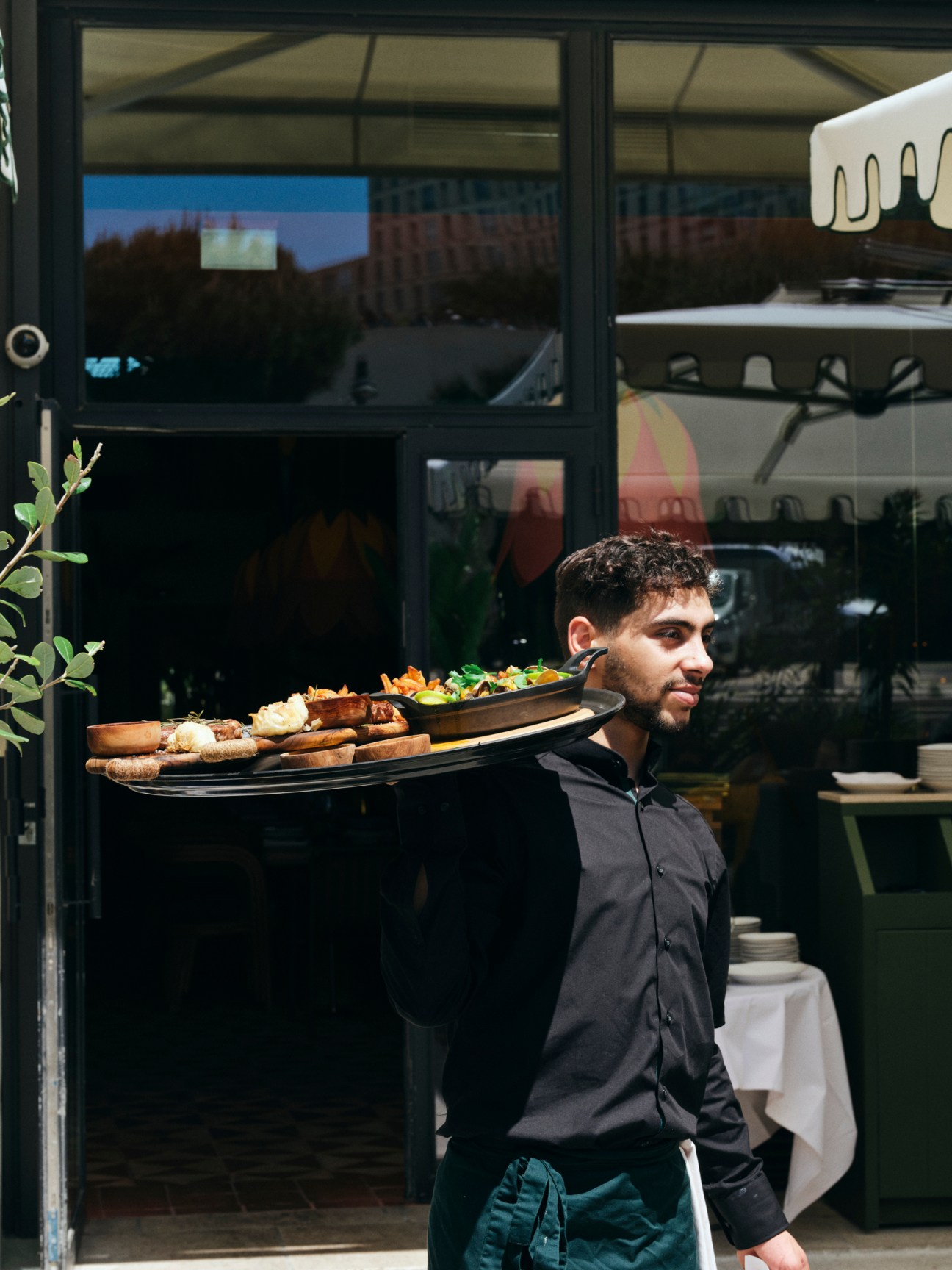 Server carrying plates of food from restaurant kitchen during lunch service