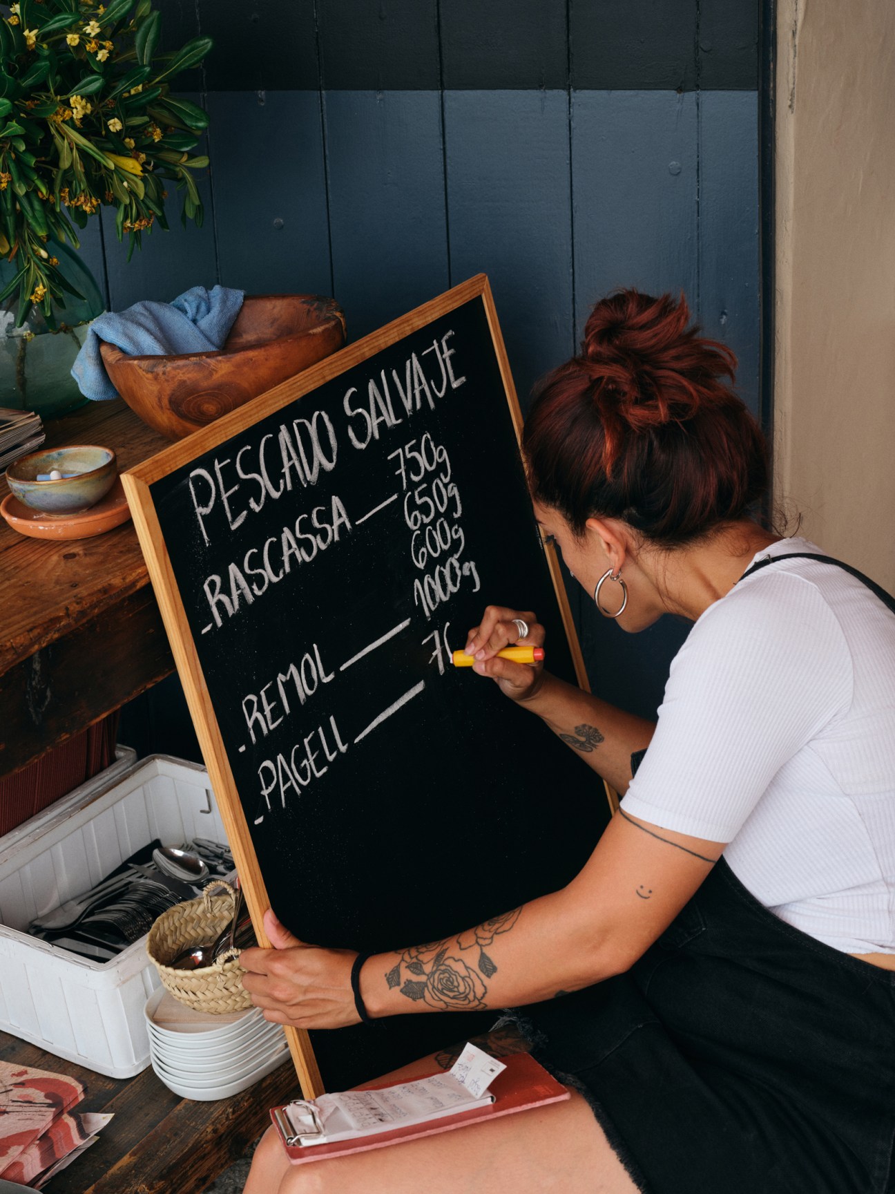 Staff member writing daily specials on chalkboard at restaurant