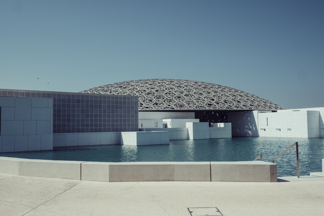 Louvre Abu Dhabi's distinctive domed roof with white perforated lattice design, surrounded by water on Al Saadiyat Island.