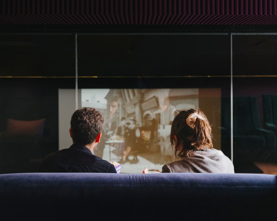 Two visitors viewing a film on a screen in La Loge, a private viewing room at Hotel Paradiso.